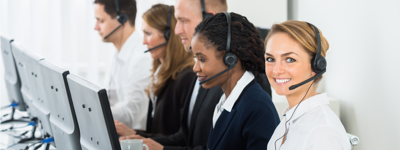 Helpdesk support workers talking in headsets and typing on computers