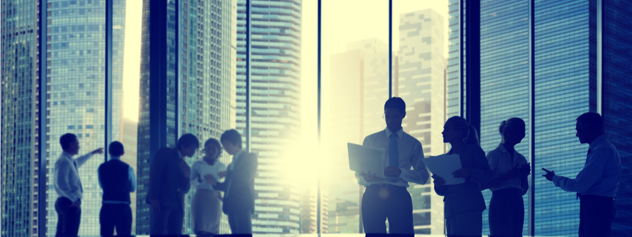 Business professionals gathered in front of large office windows