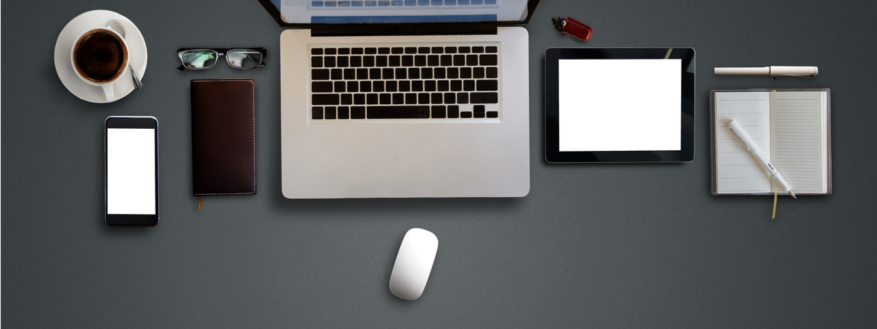 Laptop, tablet, and supplies on black desk.