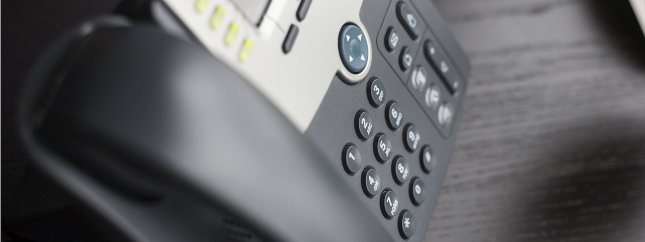 Office phone sitting on wooden desk